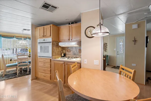 a open kitchen with stainless steel appliances granite countertop a refrigerator a oven a stove and a dining table with wooden floor