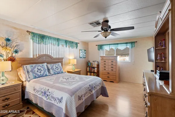 a bedroom with a bed and a flat tv screen on dresser