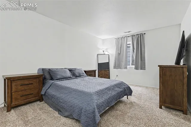 a bedroom with a bed flat screen tv and a window