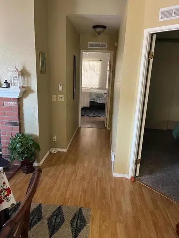 a view of a hallway to a livingroom with wooden floor and furniture