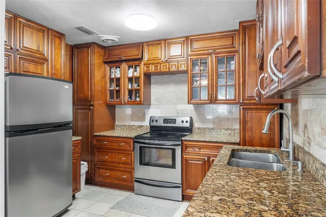 a kitchen with stainless steel appliances granite countertop a refrigerator stove and sink
