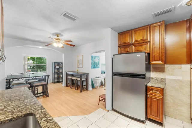 a kitchen with stainless steel appliances granite countertop a refrigerator a stove a sink a dining table and chairs with the view of kitchen