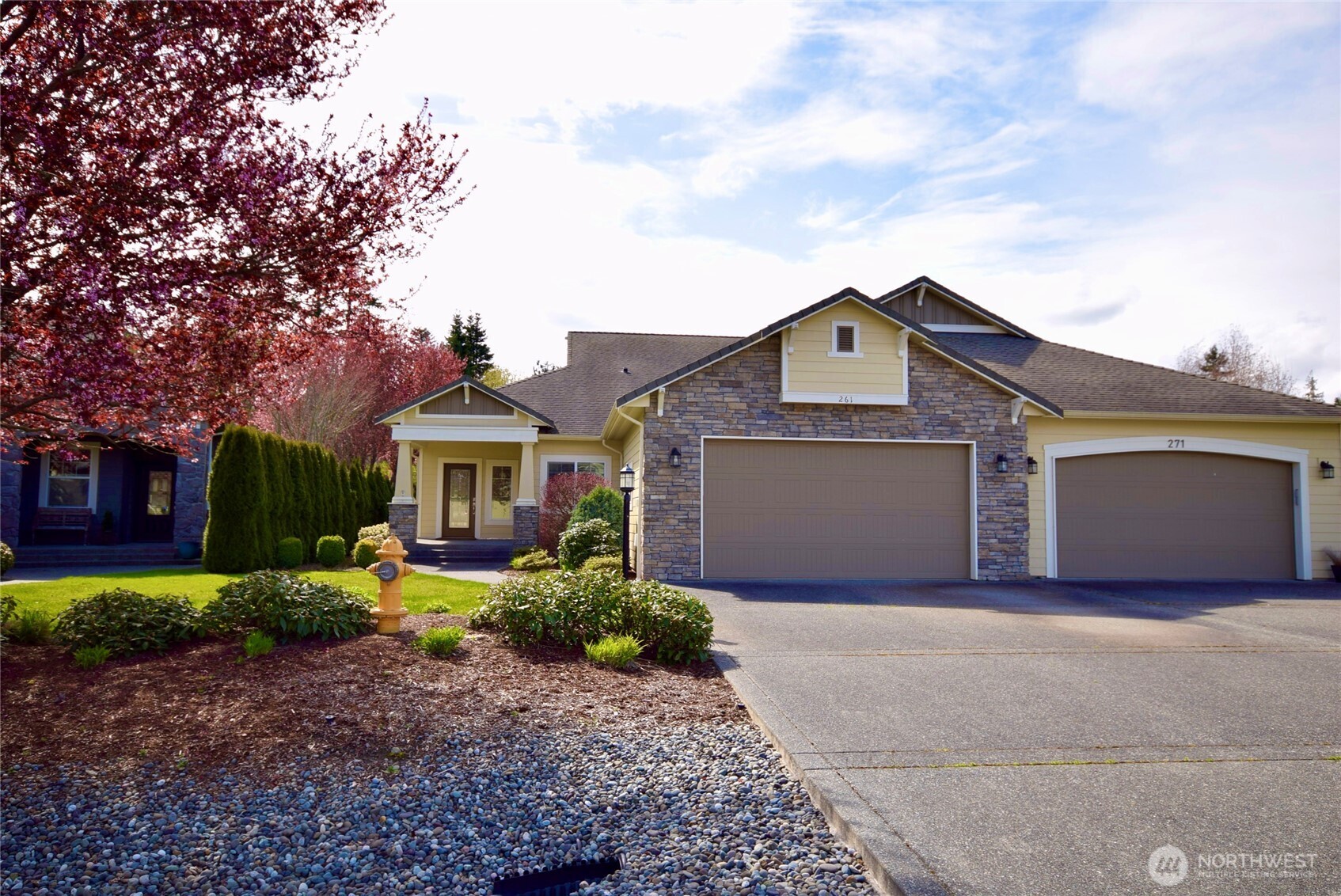 a front view of a house with a garden and trees