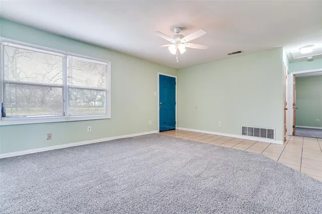 an empty room with chandelier fan and windows