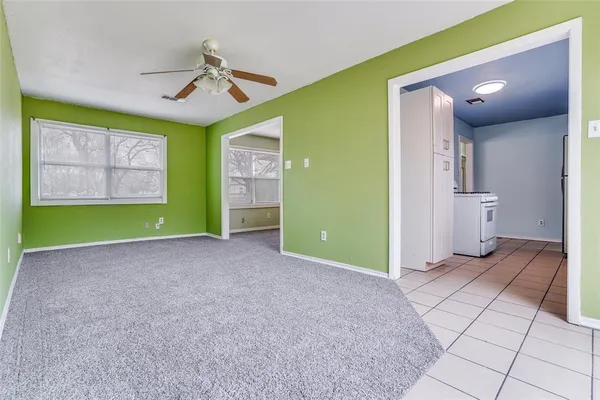 a view of an empty room with a window and a kitchen