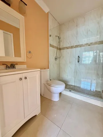 a bathroom with a granite countertop sink a toilet and a shower