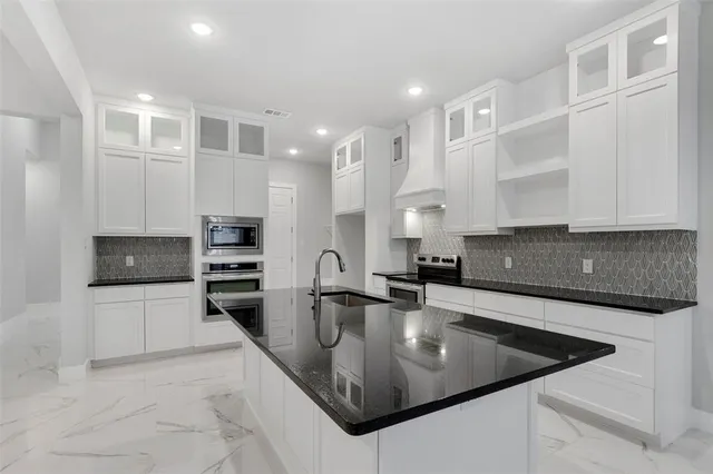 a kitchen with stainless steel appliances granite countertop a sink a stove and a refrigerator