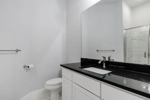 a bathroom with a granite countertop sink and a toilet