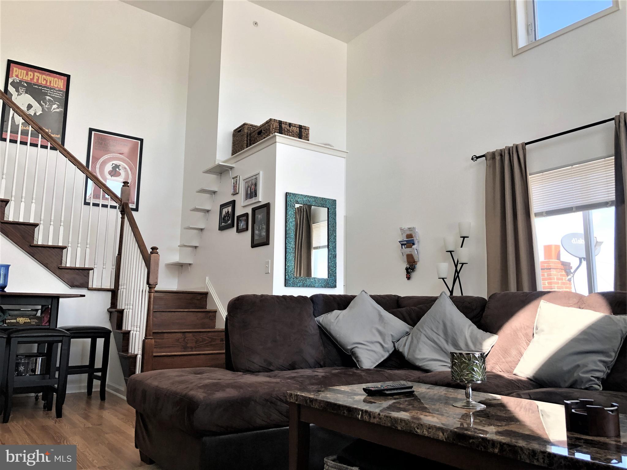 a living room with furniture kitchen view and a window
