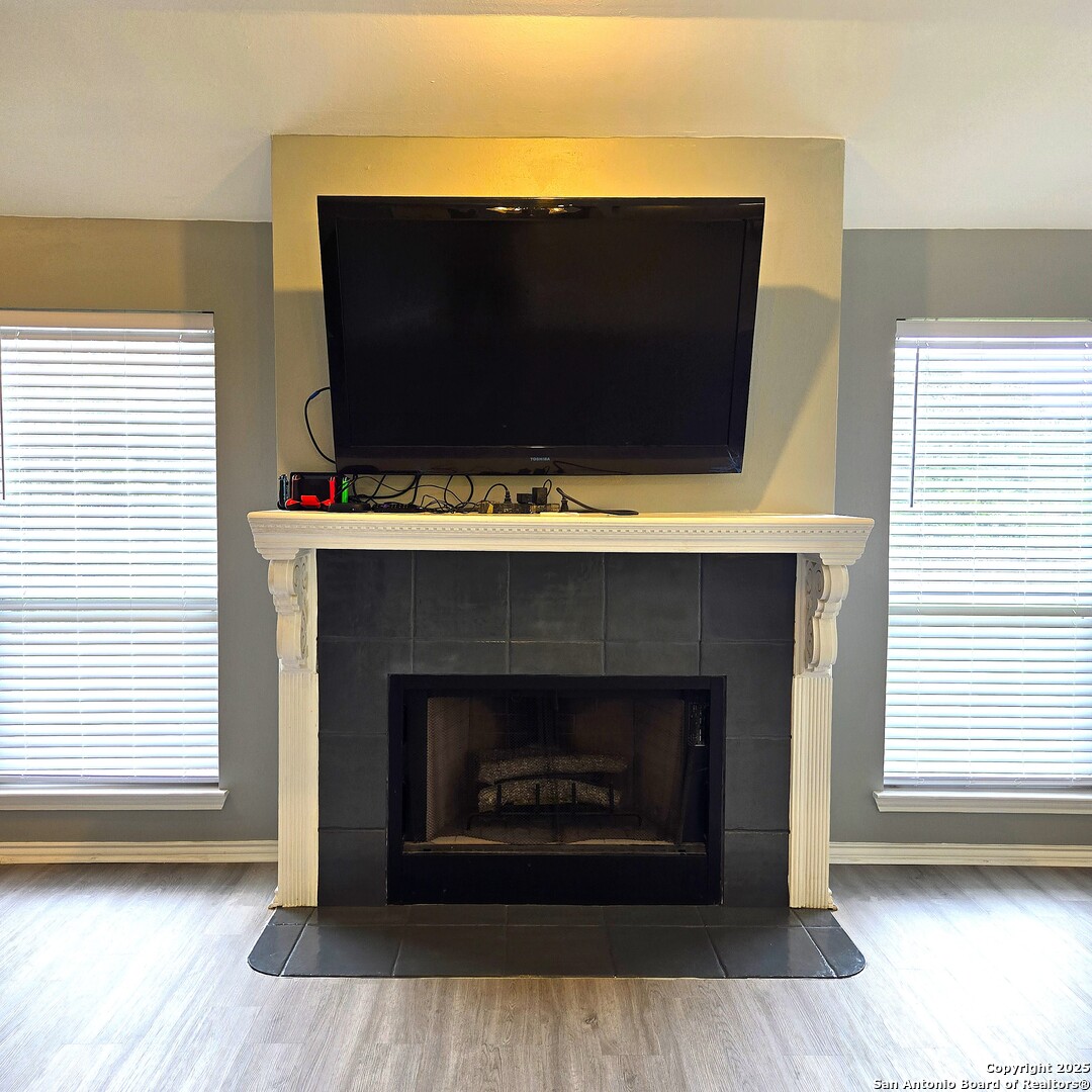 23007 South Breeze Street San Antonio, TX 78258 - Photo 11 of 27 a living room with a fireplace a flat screen tv and a window