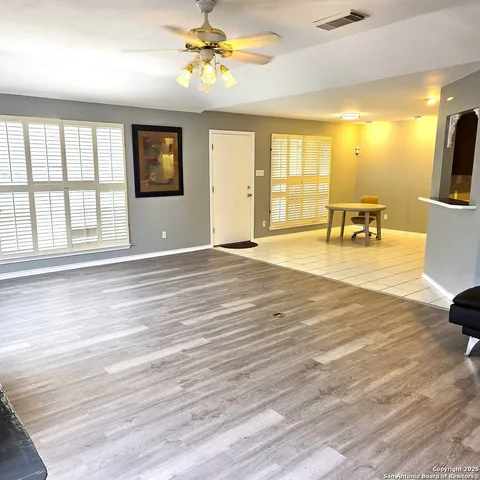 a view of an empty room with a window and kitchen view