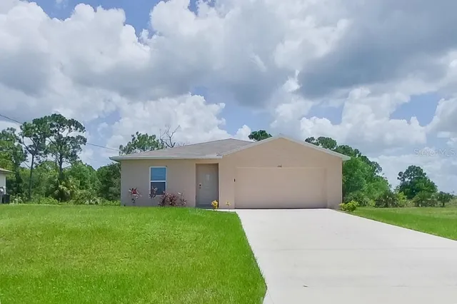 a front view of a house with a yard and a garden