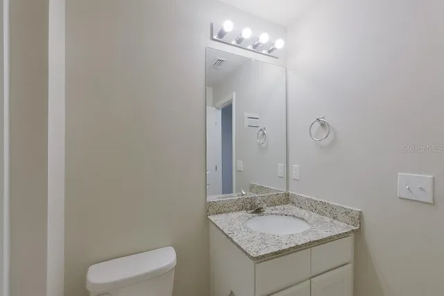 a bathroom with a granite countertop sink a toilet and a mirror