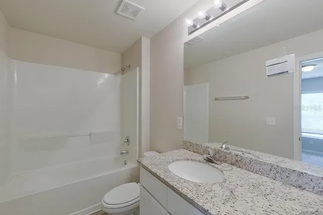 a bathroom with a granite countertop sink toilet tub and shower