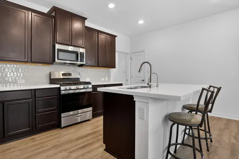 a kitchen with stainless steel appliances kitchen island granite countertop a stove top oven a sink and dishwasher with wooden floor