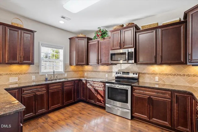 a kitchen with stainless steel appliances granite countertop wooden cabinets sink and stove
