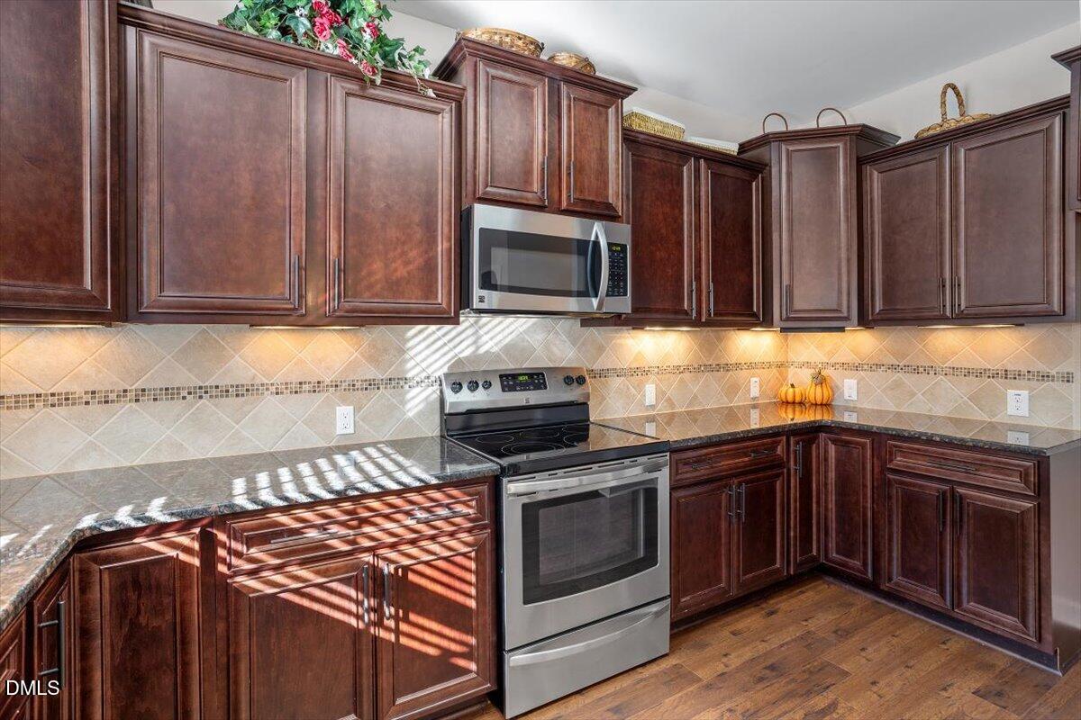 109 North Sunset Ridge Drive Willow Spring, NC 27592 - Photo 13 of 54 a kitchen with granite countertop wood cabinets stainless steel appliances and a sink