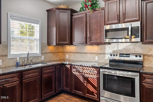 a kitchen with granite countertop a stove top oven microwave and cabinets