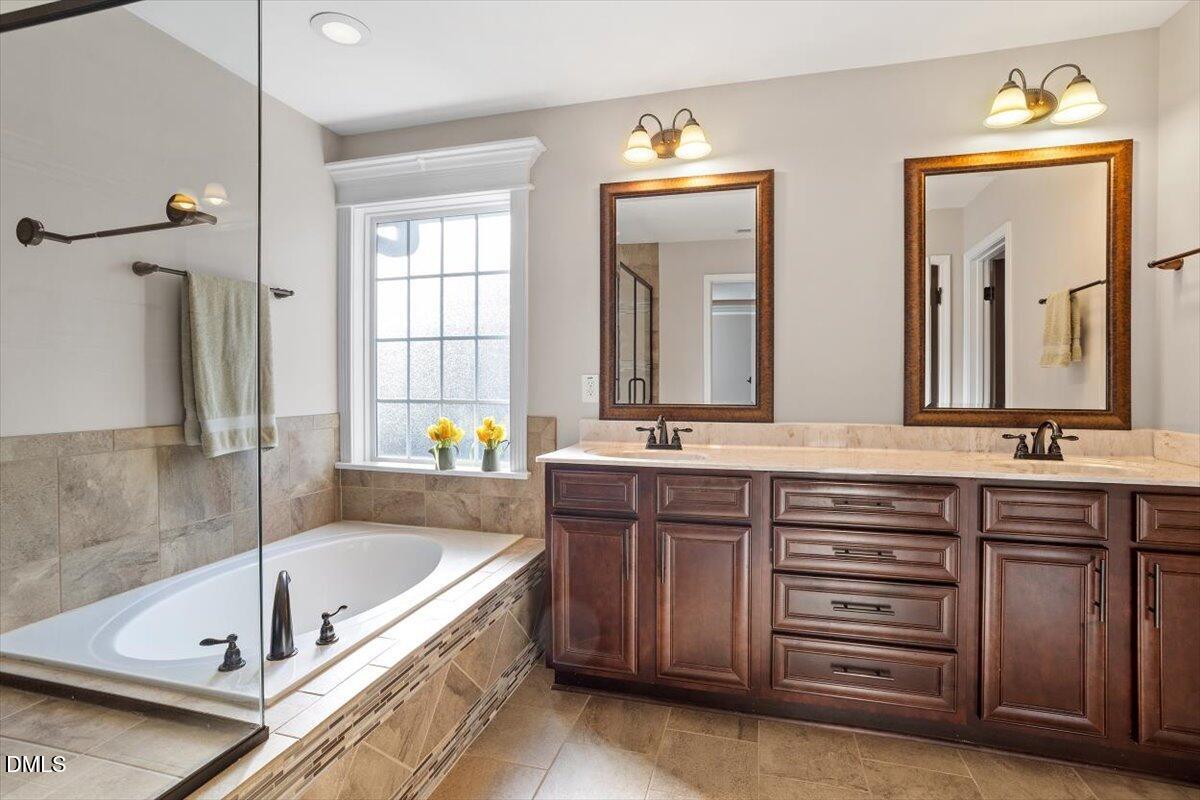 109 North Sunset Ridge Drive Willow Spring, NC 27592 - Photo 23 of 54 a bathroom with a tub a double vanity sink and a large mirror
