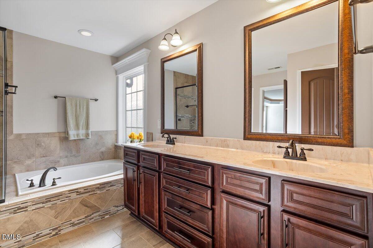 109 North Sunset Ridge Drive Willow Spring, NC 27592 - Photo 25 of 54 a bathroom with a bathtub a double vanity sink and mirror