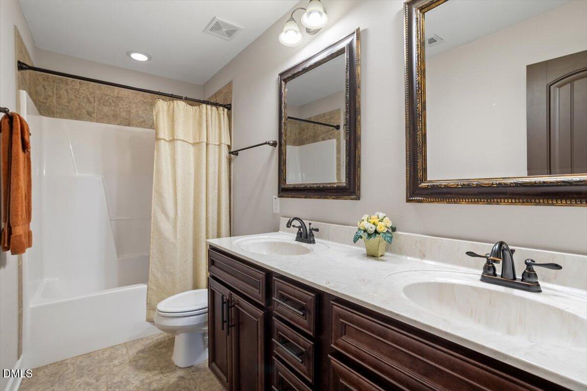 109 North Sunset Ridge Drive Willow Spring, NC 27592 - Photo 30 of 54 a bathroom with double vanity sink a toilet and a mirror