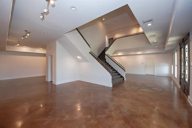 a view of an empty room with a window and a kitchen
