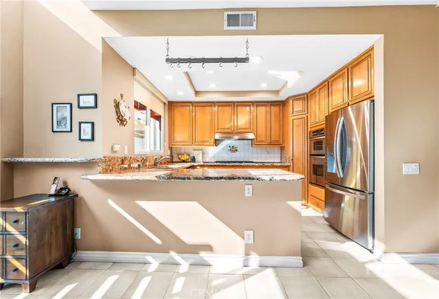 a kitchen with stainless steel appliances granite countertop a refrigerator and a stove top oven