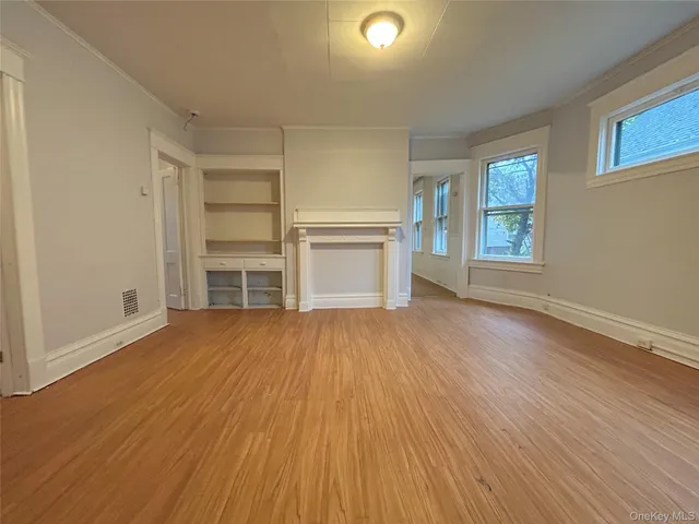 an empty room with wooden floor closet and windows