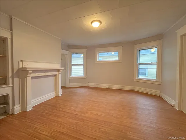 an empty room with wooden floor cabinet and windows