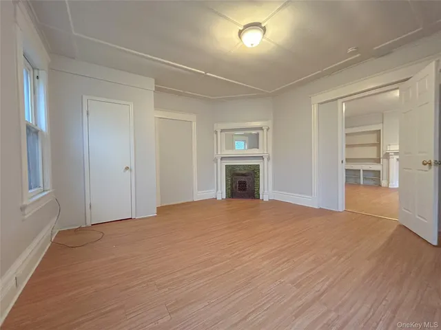 a view of empty room with a fireplace and wooden floor