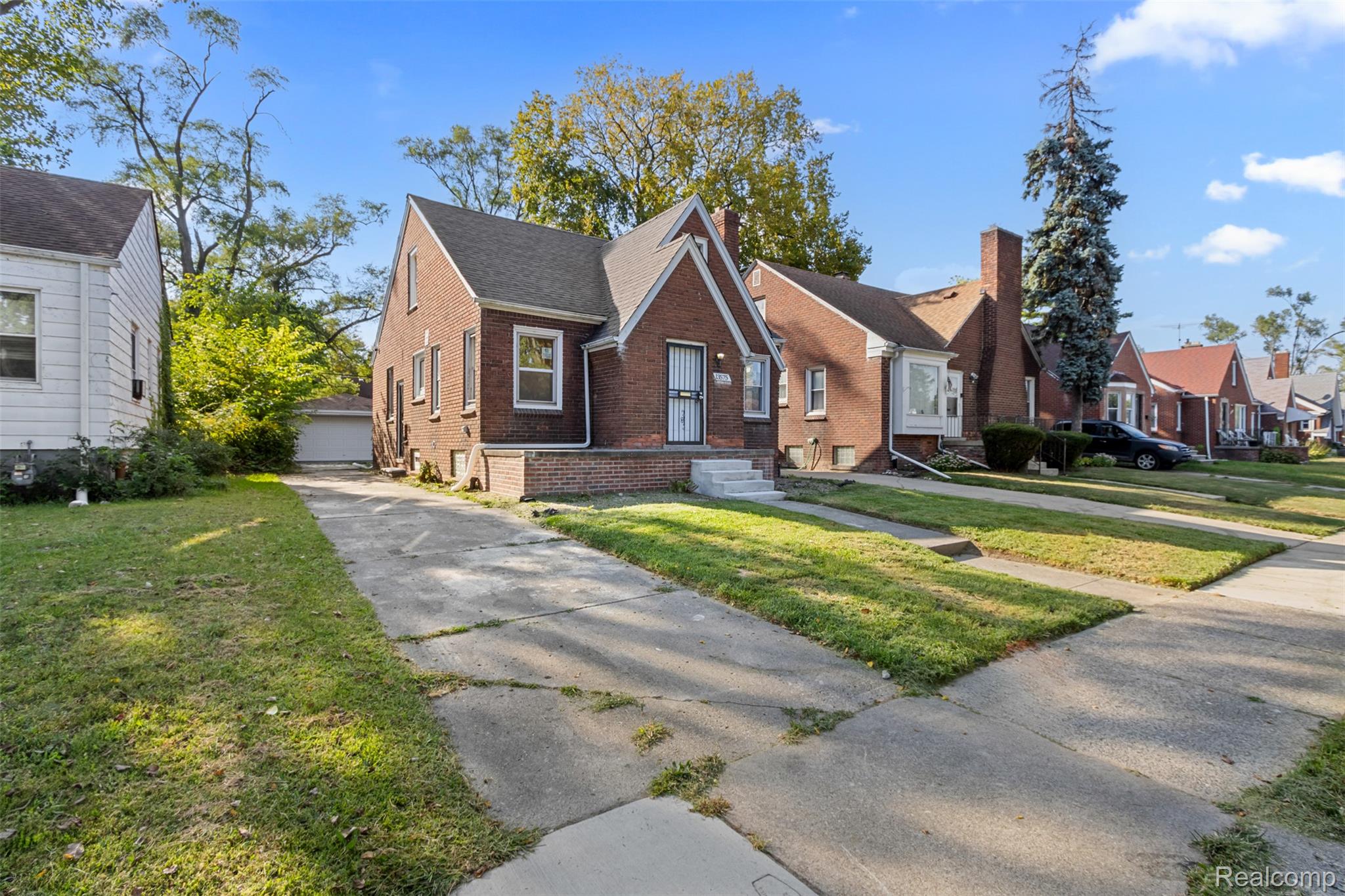 13575 Rutherford Street Detroit, MI 48227 - Photo 2 of 16 View of front of home featuring brick siding, a front lawn, a residential view, and a garage