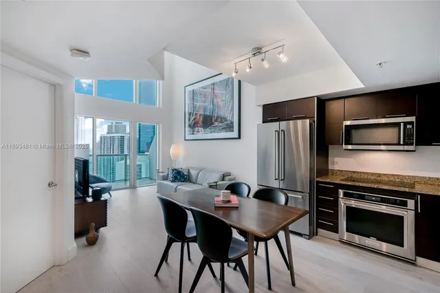 a kitchen with a table chairs stainless steel appliances and cabinets