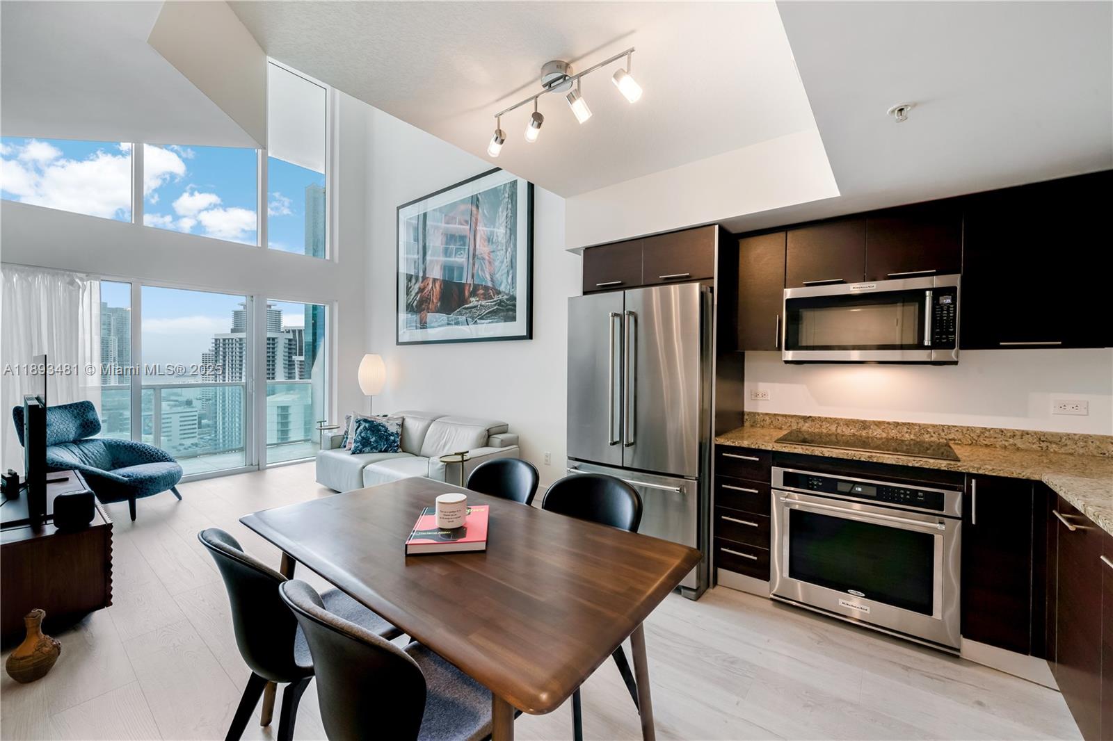 41 Southeast 5th Street, Unit 1709 Miami, FL 33131 - Photo 7 of 33 a kitchen with a stove a refrigerator and a dining table
