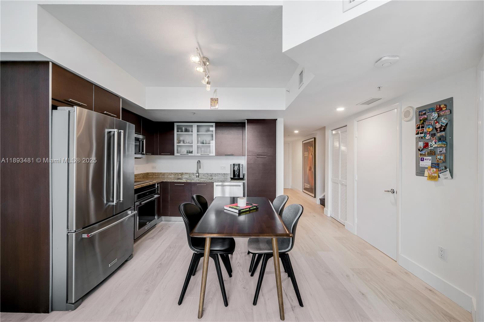 41 Southeast 5th Street, Unit 1709 Miami, FL 33131 - Photo 8 of 33 a kitchen with stainless steel appliances a refrigerator a stove a dining table and chairs with wooden floor
