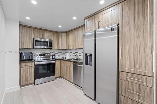 a kitchen with stainless steel appliances granite countertop a refrigerator and a stove top oven