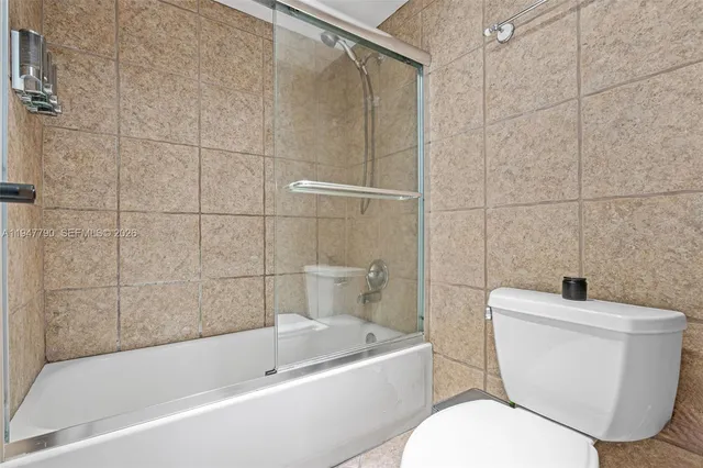 a white toilet sitting next to a bath tub and a shower