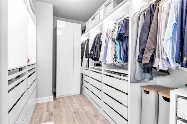 a view of walk in closet with clothes and shoes