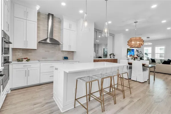 a kitchen with stainless steel appliances kitchen island granite countertop a stove a sink a refrigerator and white cabinets with wooden floor