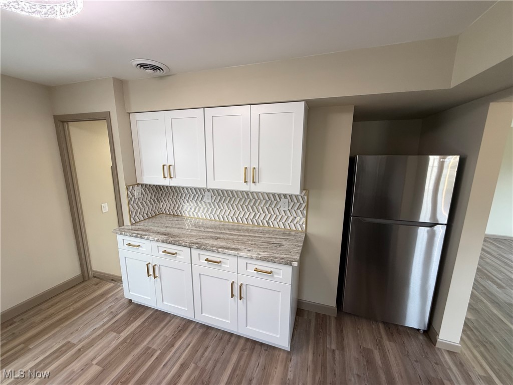 9417 Alexander Road Garfield Heights, OH 44125 - Photo 7 of 38 Kitchen featuring visible vents, white cabinets, baseboards, freestanding refrigerator, and wood finished floors