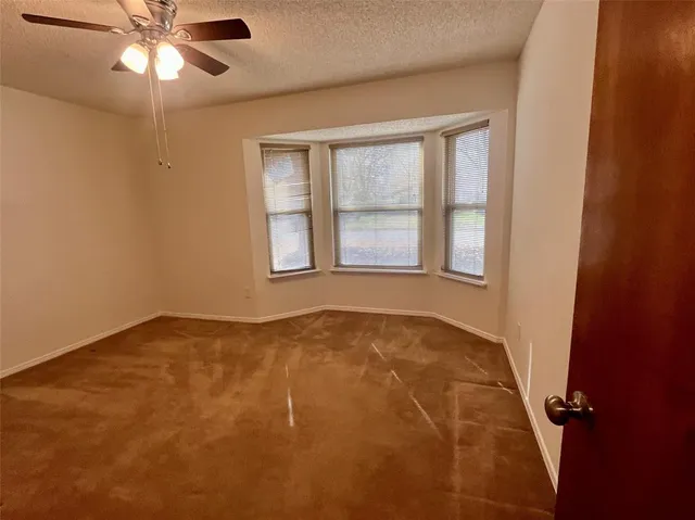 an empty room with a window and a fan