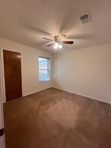 an empty room with windows and ceiling fan