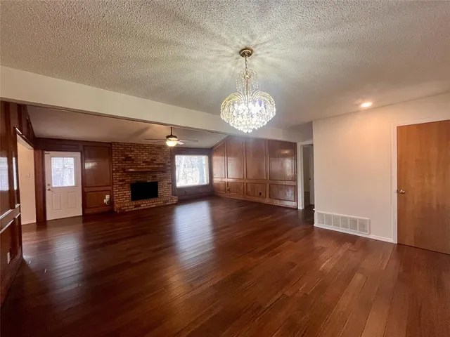 an empty room with wooden floor fireplace and windows