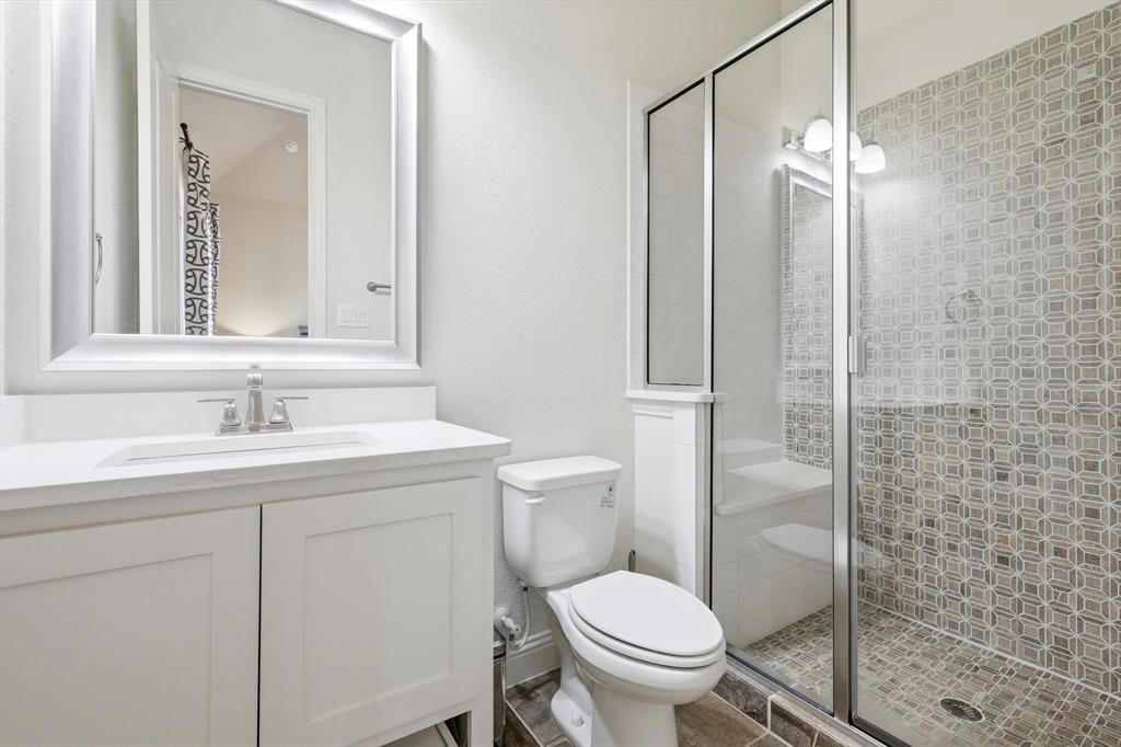 7751 Faught Road Northlake, TX 76226 - Photo 23 of 39 Bathroom featuring a white vanity with an integrated sink, brushed nickel faucet, framed mirror, toilet, and a glass-enclosed shower