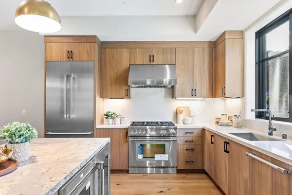 a open kitchen with stainless steel appliances granite countertop a stove a sink a oven a dining table with chairs and couches