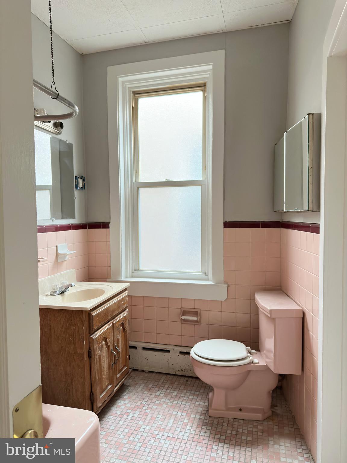 5424 Walnut Street Philadelphia, PA 19139 - Photo 7 of 7 a bathroom with a toilet a sink a mirror and a window
