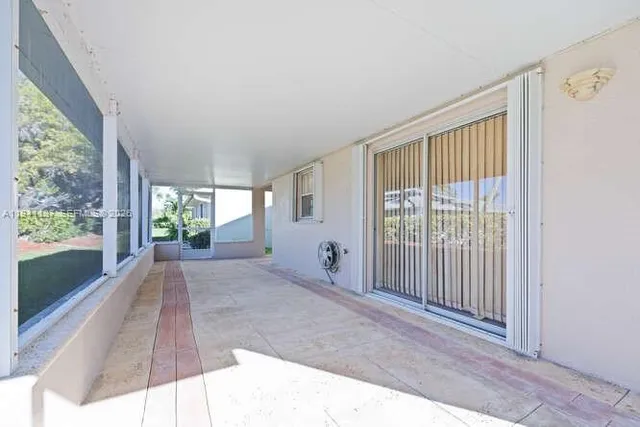 a white house that has a small yard and large trees