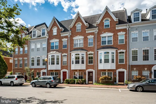 a front view of a building with lot of cars and trees