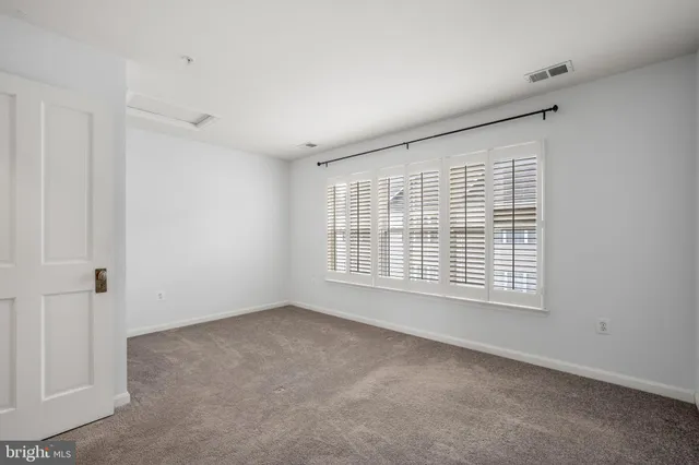 a view of an empty room with wooden floor and a chandelier fan