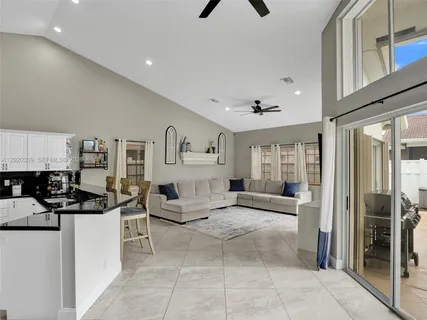 a living room with stainless steel appliances kitchen island a table chairs microwave and sink
