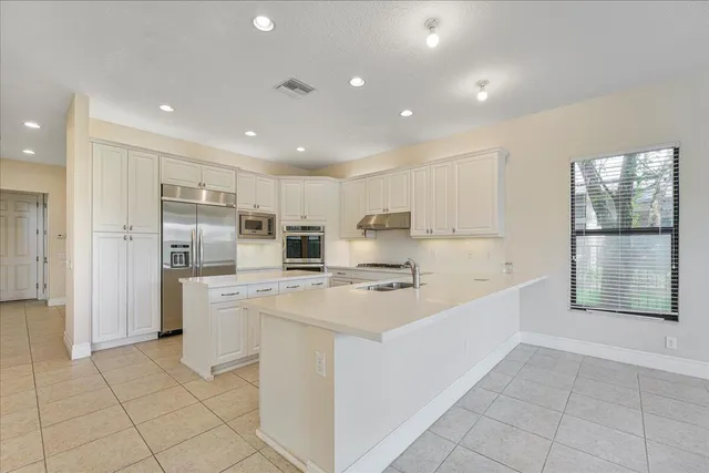 a large white kitchen with stainless steel appliances granite countertop a large counter top and a stove top oven